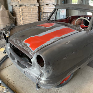 Rust and coatings partially removed from vintage car body panels by wet blasting